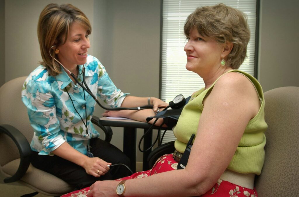 A healthcare professional measures a patient's blood pressure during a check-up in a clinical setting, promoting wellness and preventive care.