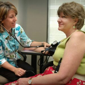 A healthcare professional measures a patient's blood pressure during a check-up in a clinical setting, promoting wellness and preventive care.