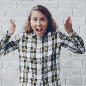 Woman with hands raised shouting in frustration.