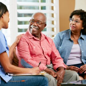 A healthcare professional converses with an elderly couple in a cozy living room, fostering a supportive dialogue about their care and well-being.