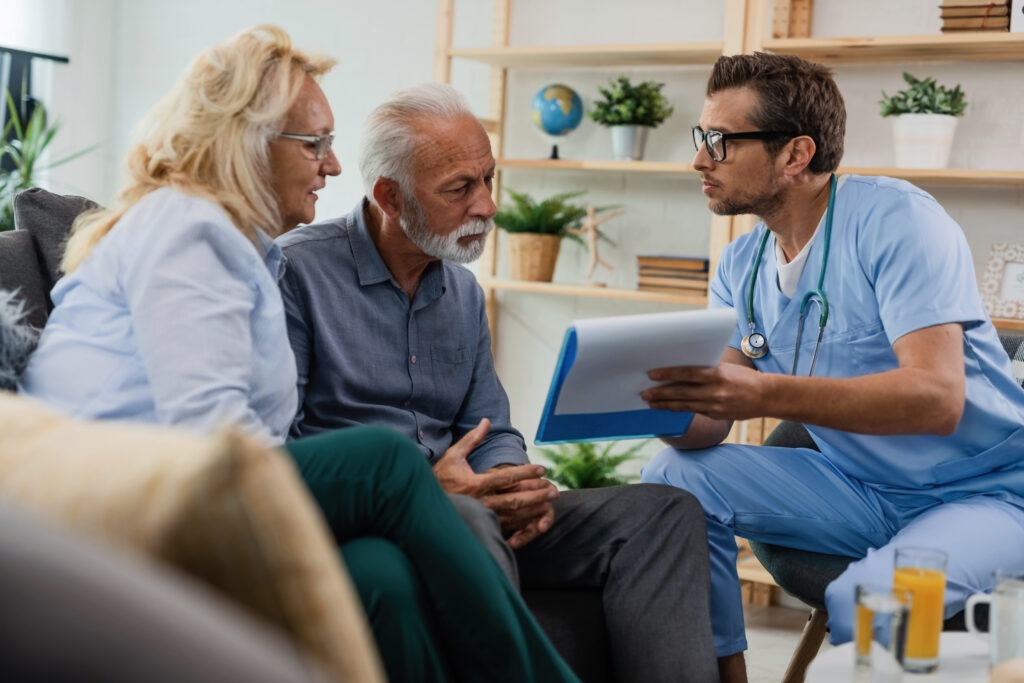 A healthcare provider discusses a treatment plan with an elderly couple in a cozy, well-lit room, emphasizing patient-centered care and communication.
