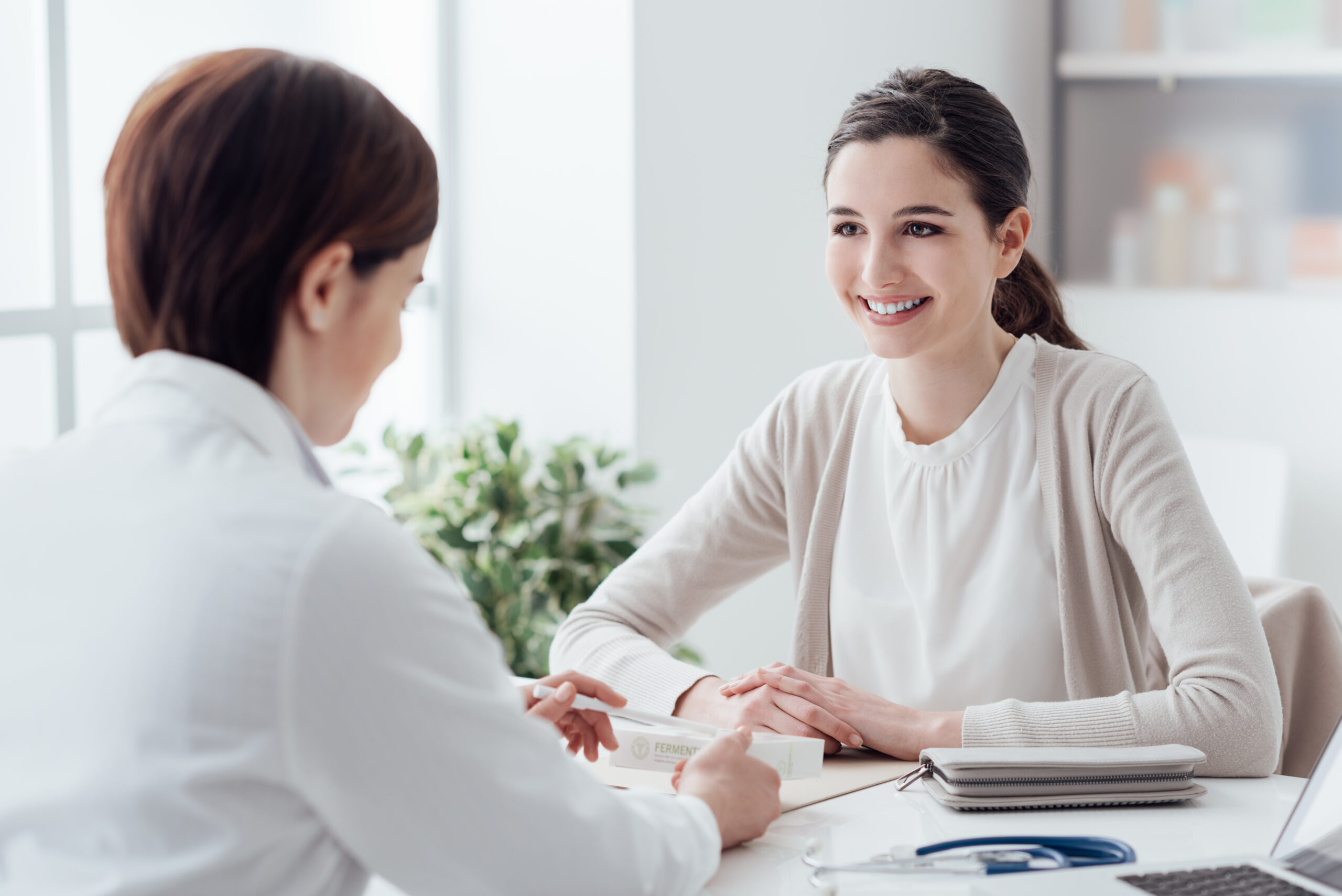 A smiling woman engages in a consultation with a healthcare professional in a bright, modern office, discussing treatment options.